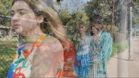 Four people dance in a line in front of Austin State Hospital. The image has been manipulated so the people are duplicated, translucent, and blurred.
